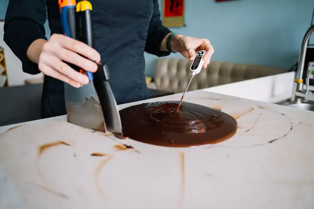 Chocolatier demonstrating tempering techniques to guests